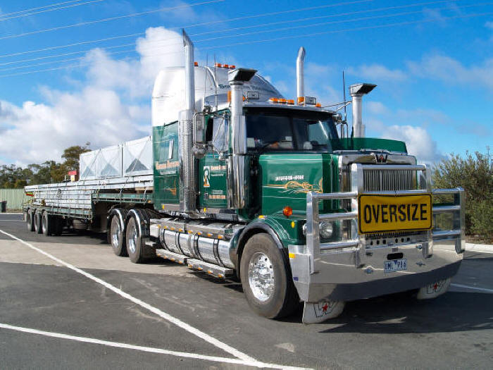  Green Western Star tractor with cattle guard and step-deck flatbed trailer, oversize load 