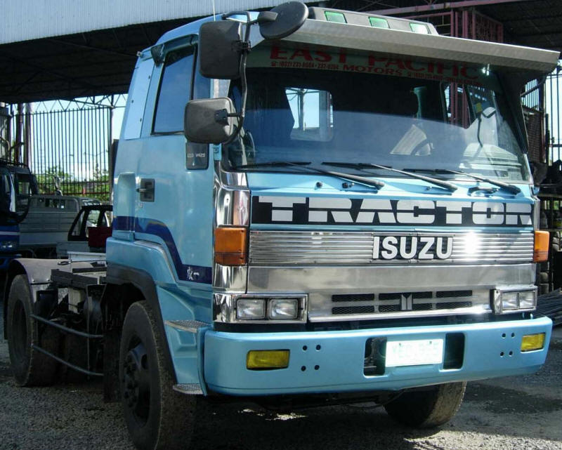 light blue Isuzu tractor truck with sun visor