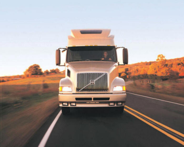 White Volvo Truck tractor trailer cruising on highway 18 wheeler